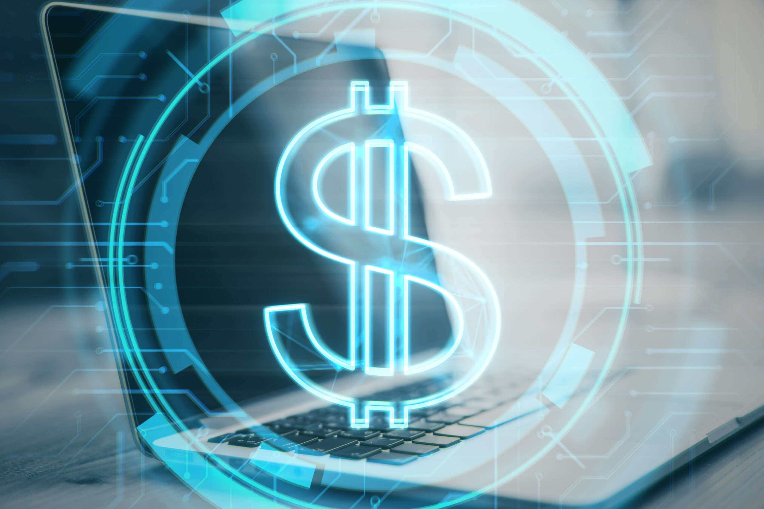 Close up of desktop with laptop and glowing dollar sign on blurry background. Money and online banking concept. Double exposure
